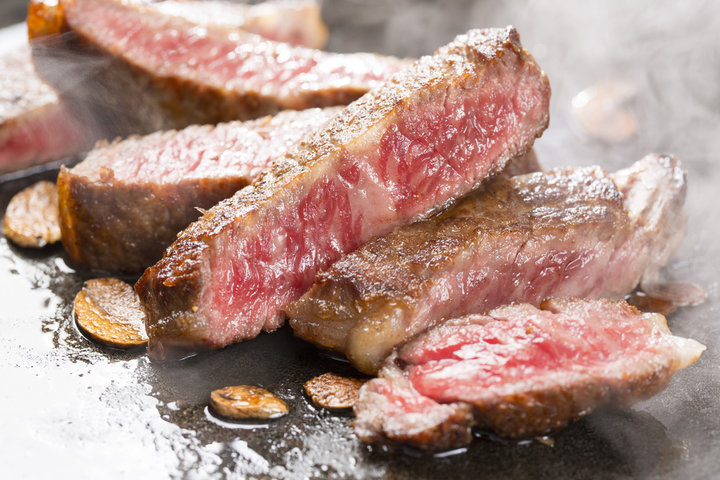 鉄板の上でじっくりと焼かれている肉厚なステーキの様子