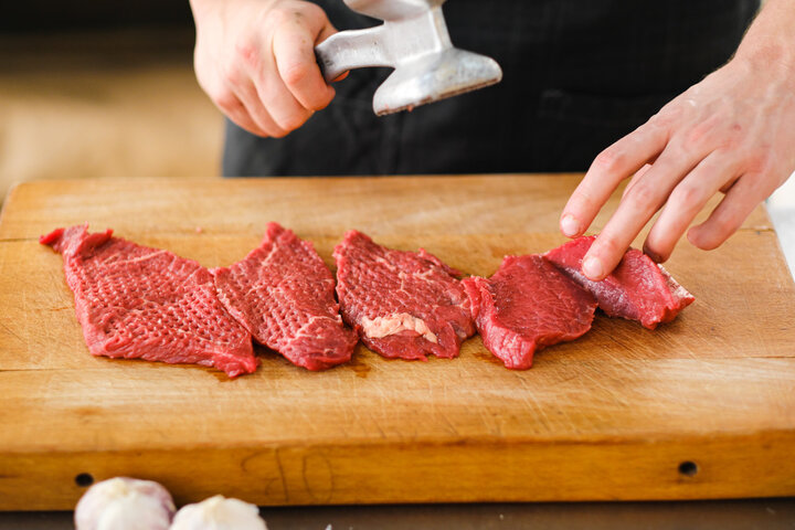 ミートハンマーの平面を使って牛肉の繊維を均一にほぐす下ごしらえの様子